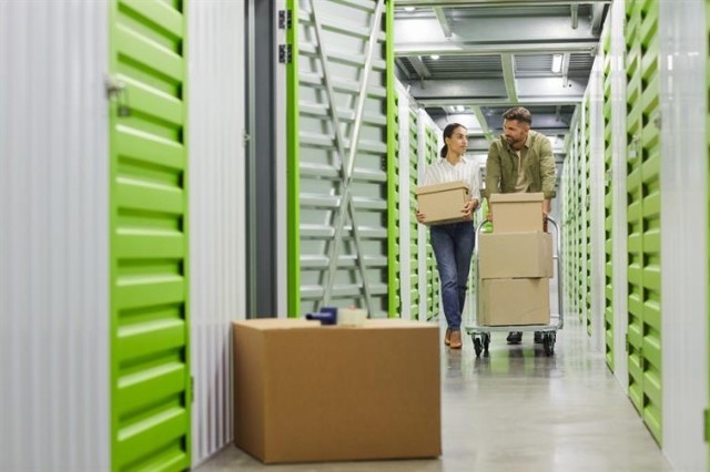 Man and woman wheeling boxes through a storage unit