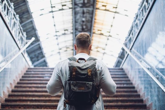 A man walking up a set of stairs into what appears to be a train or airport terminal