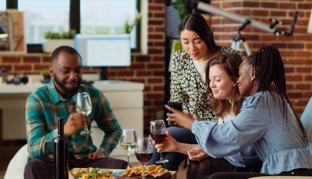 Friends enjoy food and beverages in an apartment entertainment area.