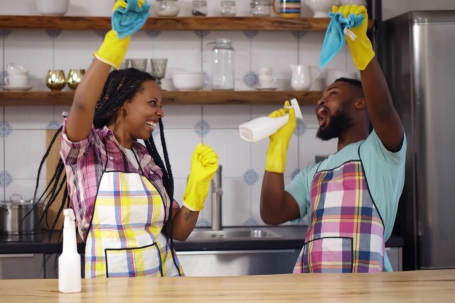 Couple dancing while cleaning.