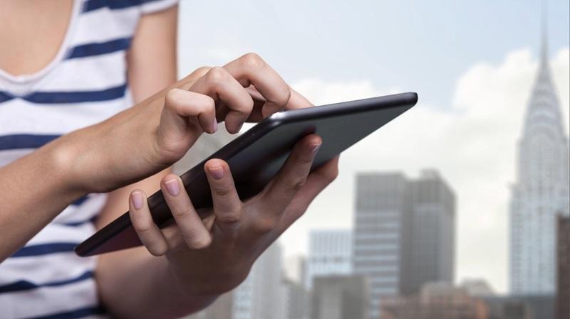 Renter searches for apartments on tablet with cityscape in background