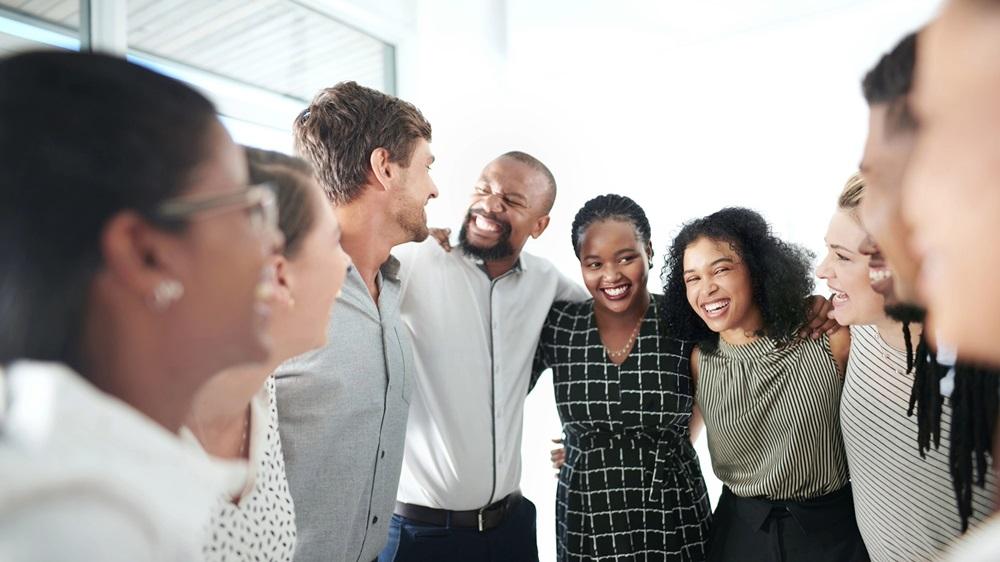 Employees smile with arms around each other