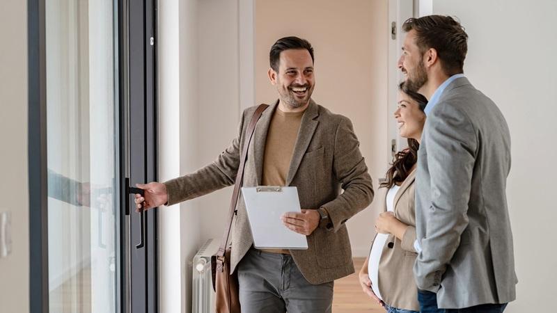 Couple walks through rental apartment on guided tour with agent