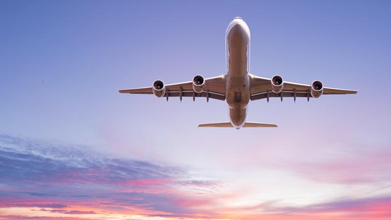 Plane flying against sunset backdrop