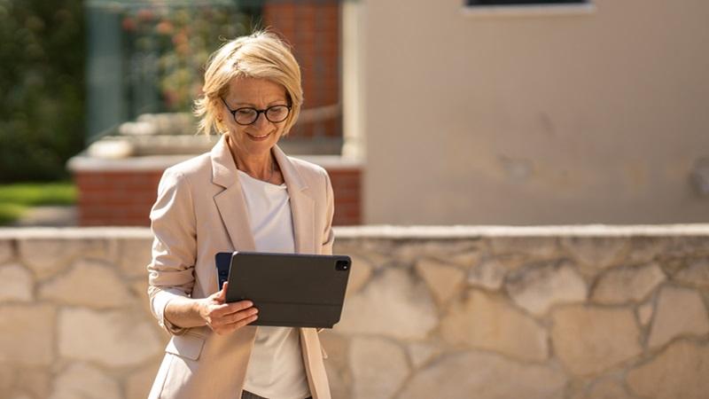 Woman looks at tablet outside residential property