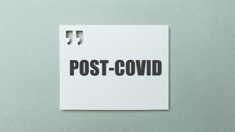 A sign with quotation marks above the word post-covid