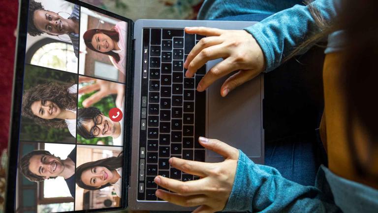 person typing on video call on laptop