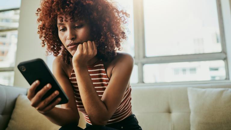 Woman sitting on couch and looking at smartphone