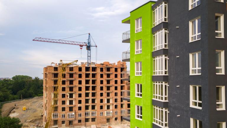 Green apartment building stands next to construction site