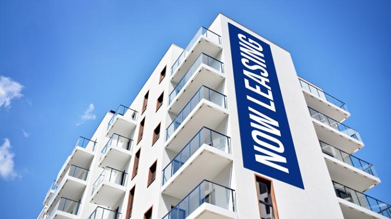 "Now leasing" sign on side of apartment building