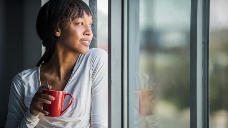 Woman holding coffee cup gazes out window