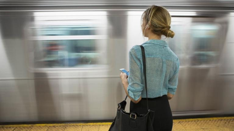 Woman stands on subway platform as train whizzes past