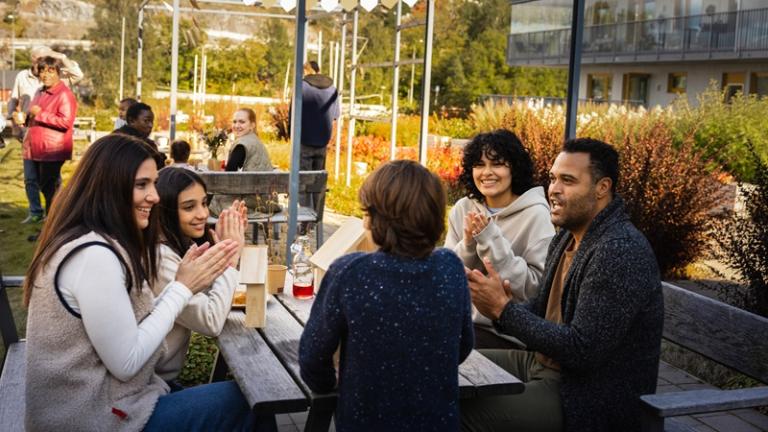 Residents sitting in outdoor apartment courtyard for spring gathering