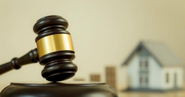 A gavel sitting next to a miniature home