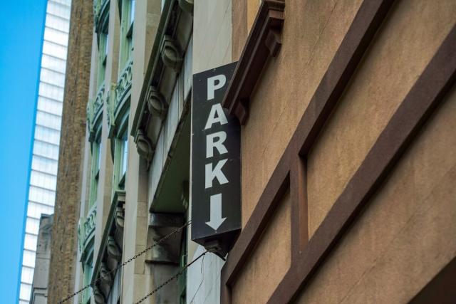 A sign that says “PARK” points to the entrance of a parking garage in a big city.