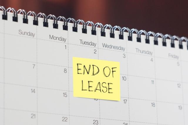 A paper calendar is marked with a yellow sticky note that reads "END OF LEASE."