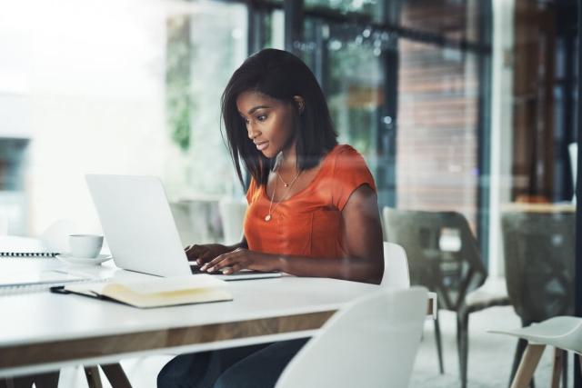 Woman sitting in a cafe typing on her laptop.