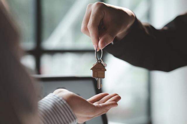 Hand dropping a home key into someone else's hand.