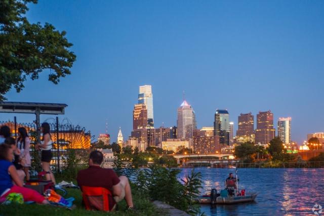 Looking at the Philadelphia skyline over a river during the evening.