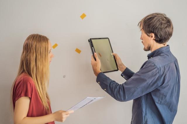 A landlord and tenant inspect damage to a wall in a rental.