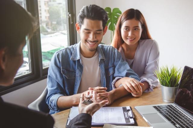 Man and woman getting an apartment key from a landlord.