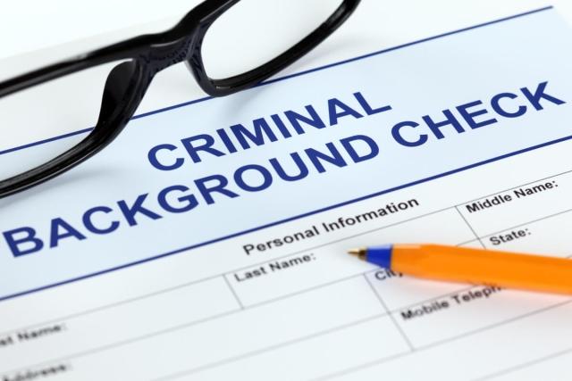 Glasses and pen on top of criminal background check application.