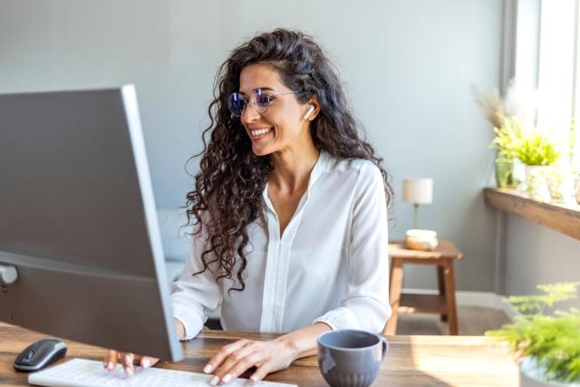 Woman smiling and typing on computer.