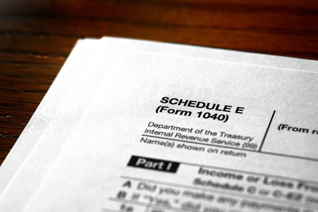 Schedule E (Form 1040) sitting on table.