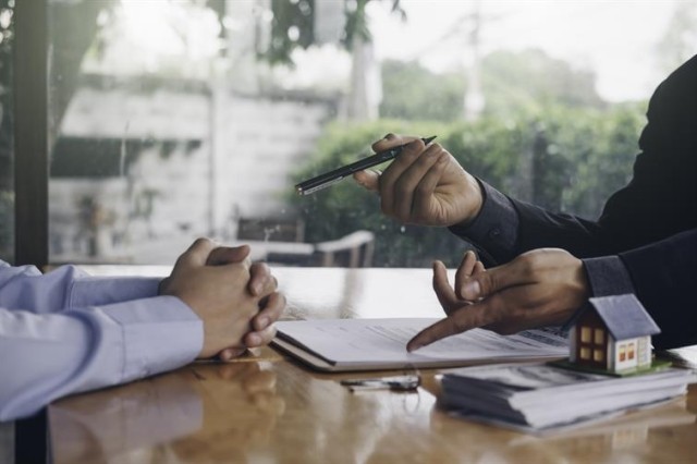 Two people sitting across from each other at a table discussing paperwork