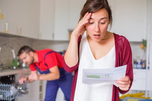 Tenant looking shocked at bill with a handyman in the background.