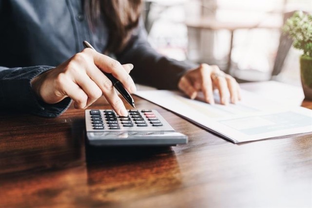 woman holding a pen while using a calculator