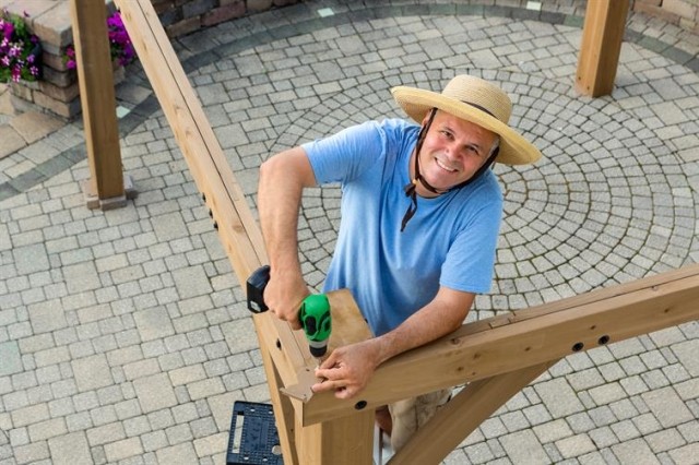 A man works on at home construction with a green drill