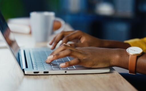 sideview photo of hands typing on a laptop keyboard