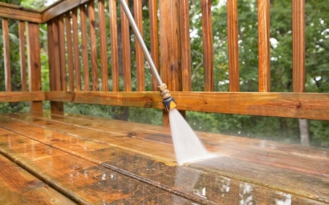 A power washer washing a deck