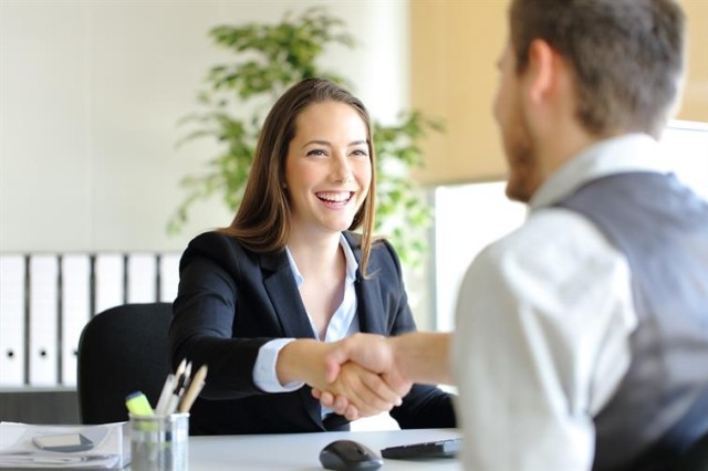 Two professional adults shake hands over a table