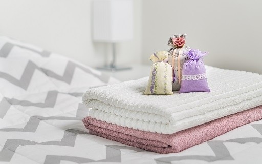 Folded towels and fragrance satchels on bed