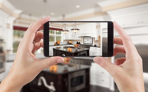 A pair of hands holding a smartphone, taking a video of a kitchen