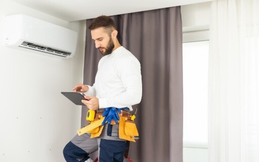 A person holding a tablet with a tool belt on, inside a rental home.