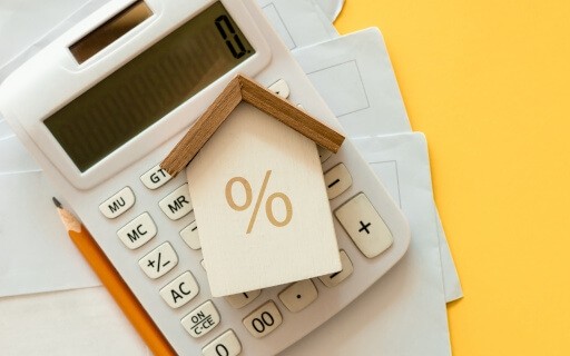 An image of a small wooden house on top of a calculator.