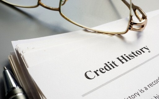A pair of reading glasses rests on a credit history report.