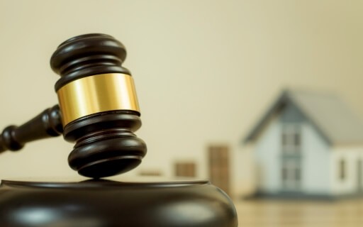 A gavel sitting next to a miniature home