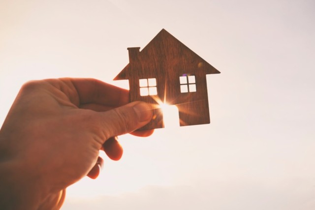 A hand holding a cut-out of a house