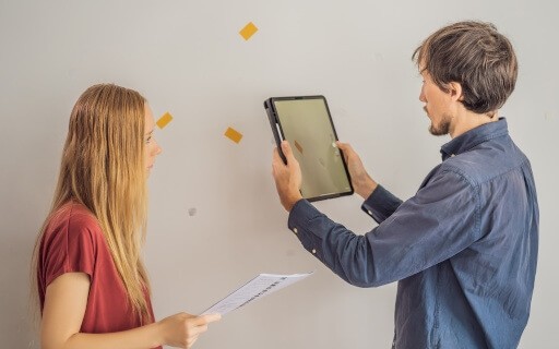 A landlord and tenant inspect damage to a wall in a rental.