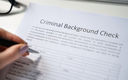 A manicured hand starts to fill out an empty background check form.
