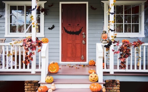 The porch and door of a house decorated with Halloween decorations.